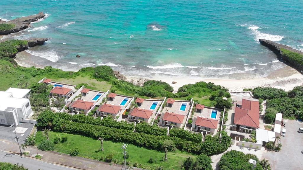 eine Luftblick auf einen Strand mit Häusern und das Meer in der Unterkunft Villabu Resort in Miyako-jima