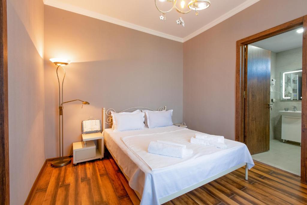 a bedroom with a large white bed and a bathroom at 4 Rooms in Sighnaghi