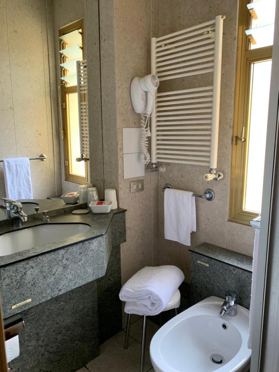 a bathroom with a toilet, sink and mirror at Hotel Roma in Aosta