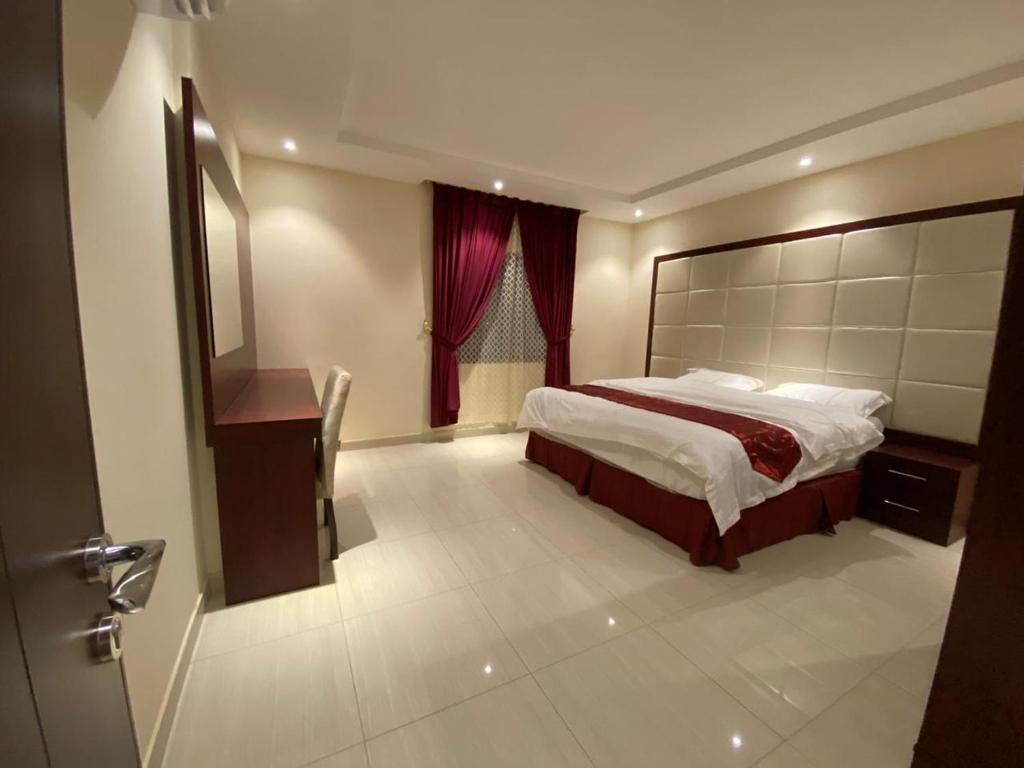 um quarto com uma cama grande e uma cortina vermelha em Al Hayat Al Marina Suites em Tabuk