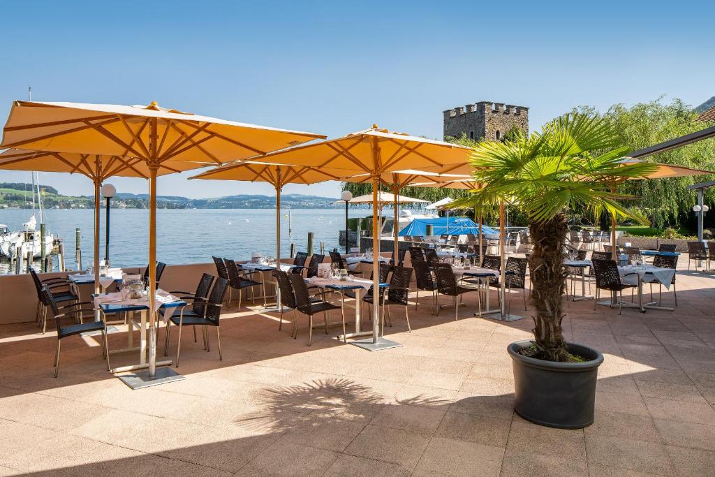 a patio with tables and chairs and umbrellas at Hotel Winkelried am See in Stansstad