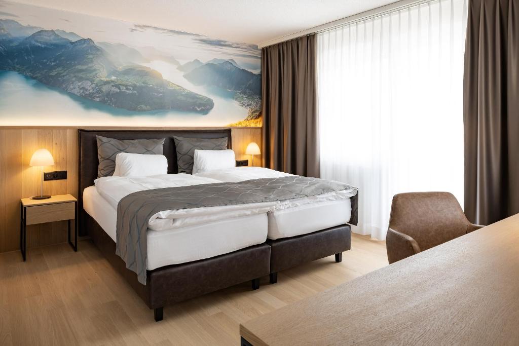 a hotel room with a large bed and a chair at Hotel Winkelried am See in Stansstad
