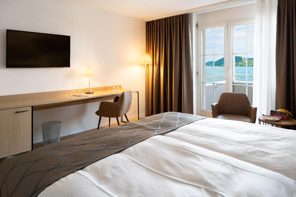 a hotel room with a bed and a desk at Hotel Winkelried am See in Stansstad