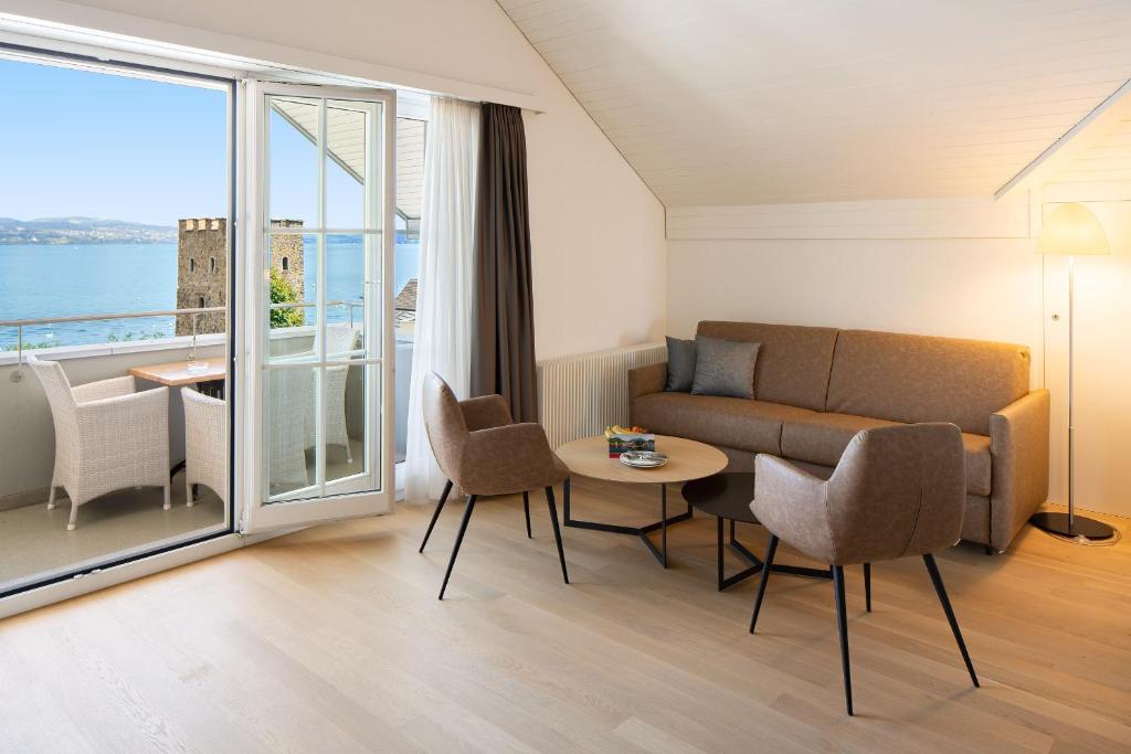 a living room with a couch and a table with chairs at Hotel Winkelried am See in Stansstad