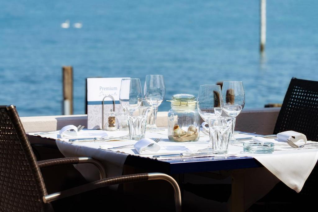 a table with wine glasses on it with the ocean in the background at Hotel Winkelried am See in Stansstad