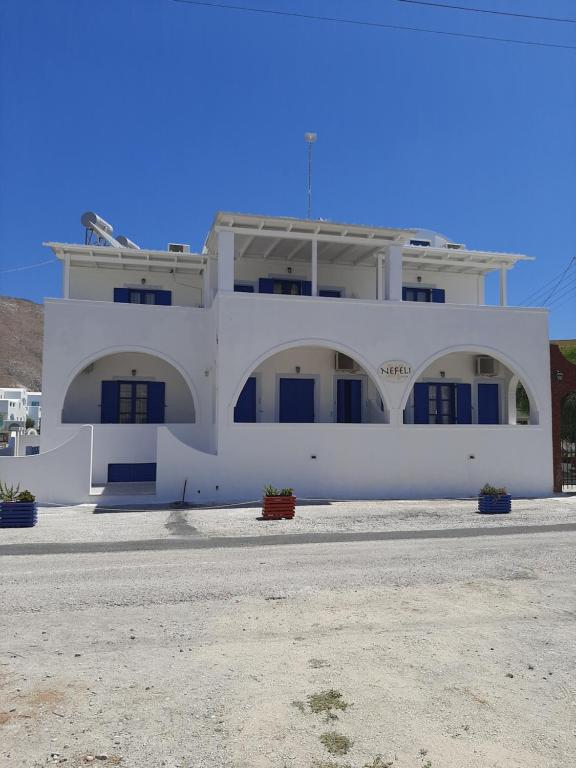 a white building with two arches in front of it at Villa Nefeli in Perissa