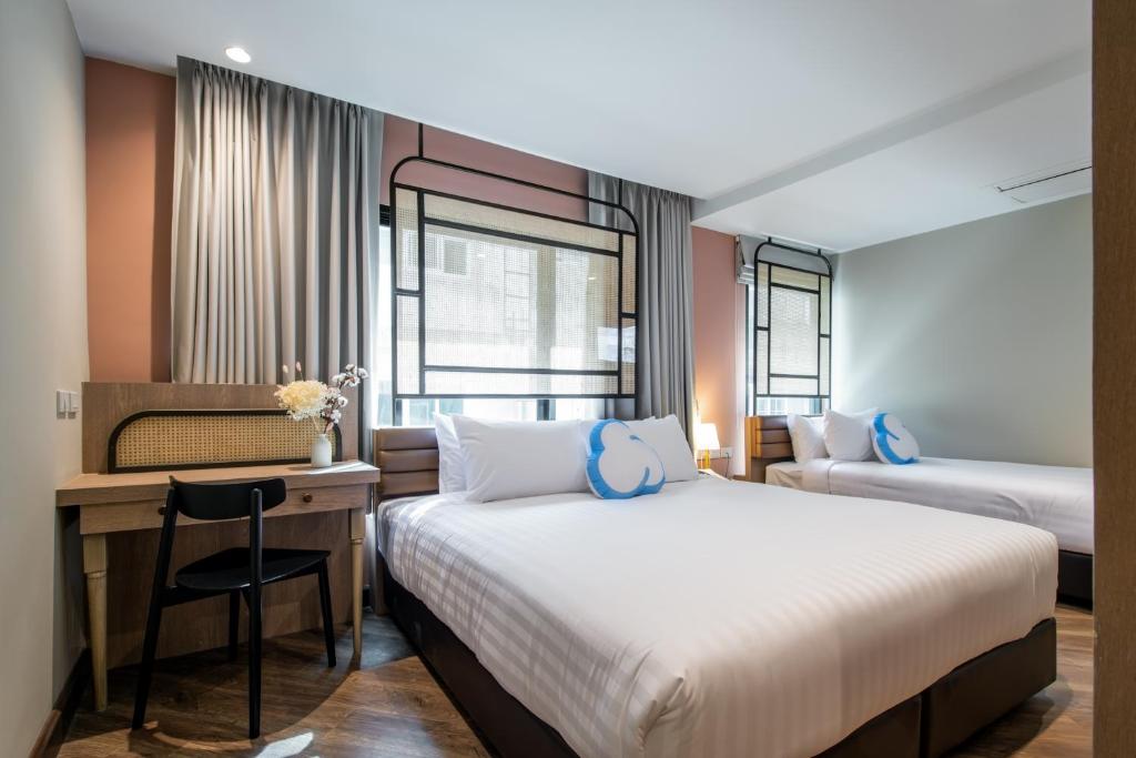 a hotel room with two beds and a desk with a chair at The Cotton Saladaeng Hotel in Bangkok