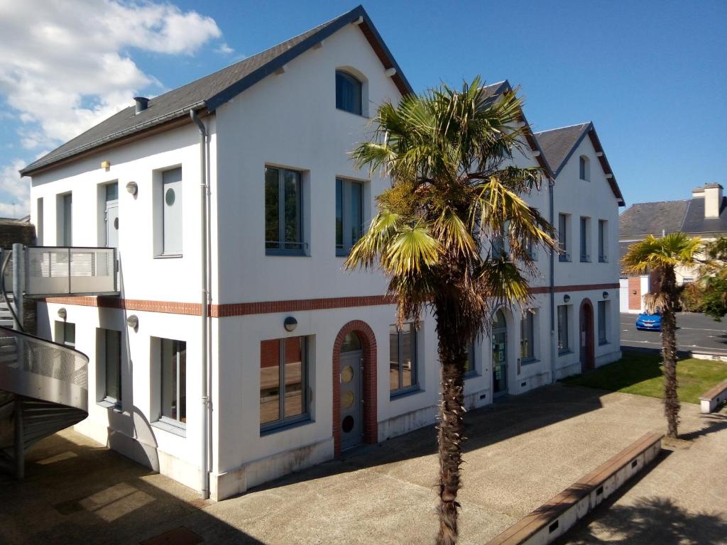 a white building with a palm tree in front of it at Auberge de Jeunesse HI Cherbourg in Cherbourg en Cotentin