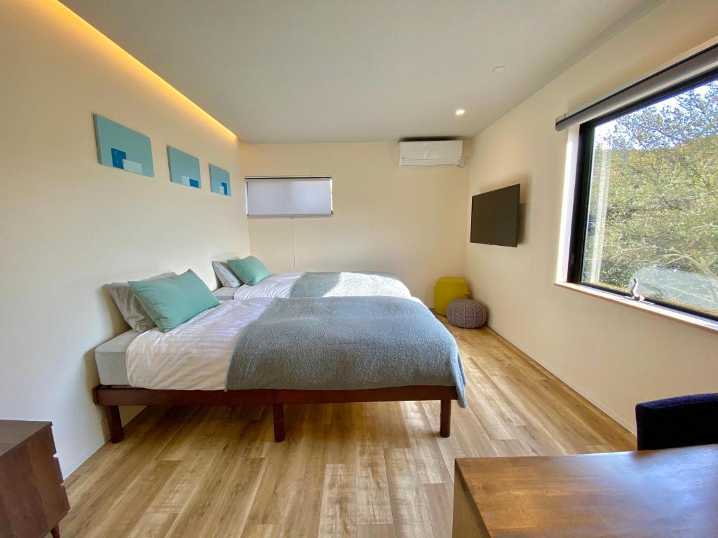 een slaapkamer met een bed en een groot raam bij BATONWORKS Naoshima in Naoshima