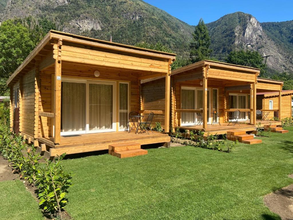 Cabaña de madera con porche y césped verde en Camping Piccolo Paradiso, en Avegno