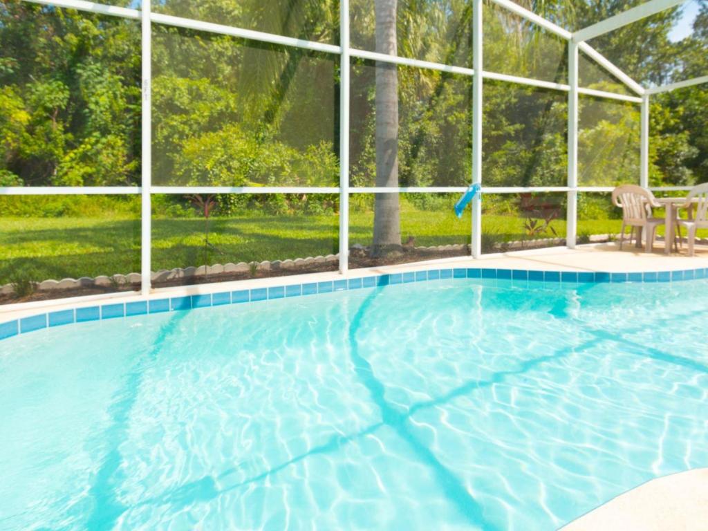 a swimming pool with two chairs in front of a building at Sunshine, Love, And Happiness In A Home Thats Cute As A Button - 3bd 2552 in Kissimmee