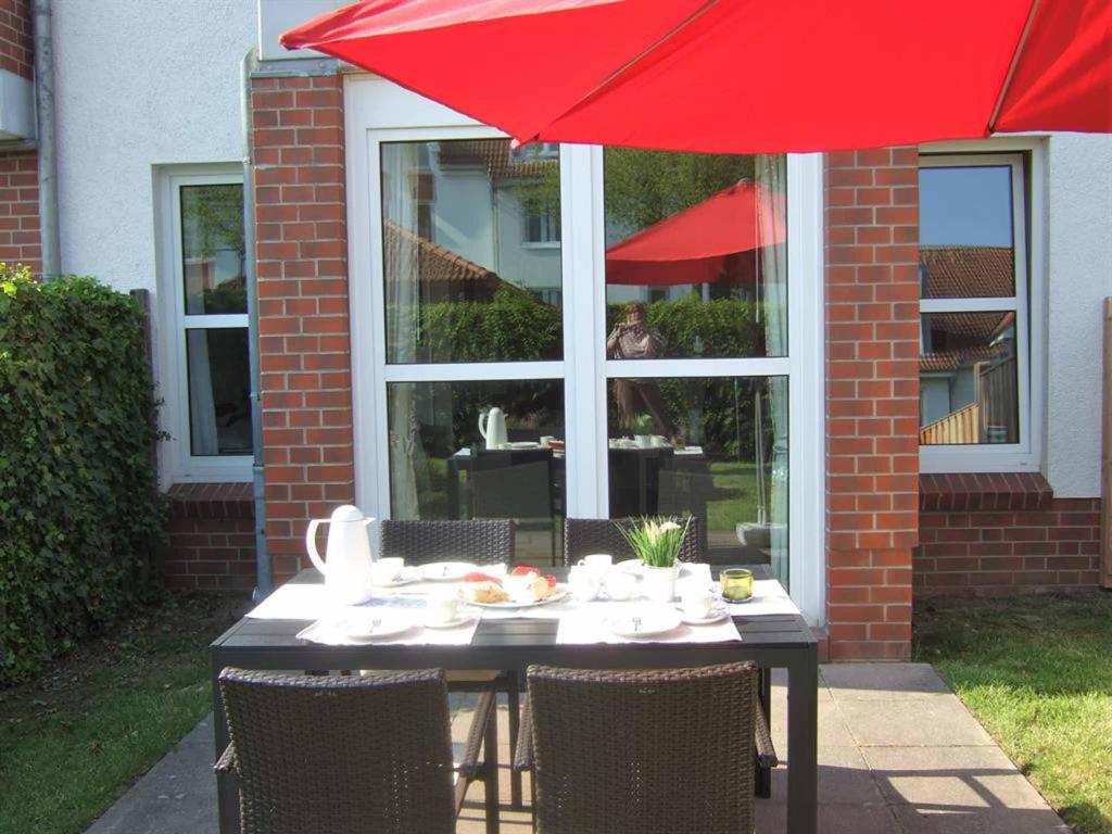 een tafel met een rode paraplu voor een gebouw bij Ferienwohnung Ostseeglück in Boltenhagen