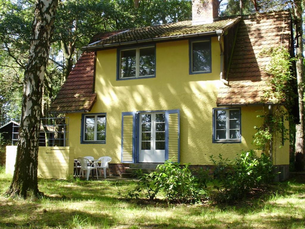 a yellow house with a table and chairs in front of it at Ferienhaus am Beetzsee in Päwesin
