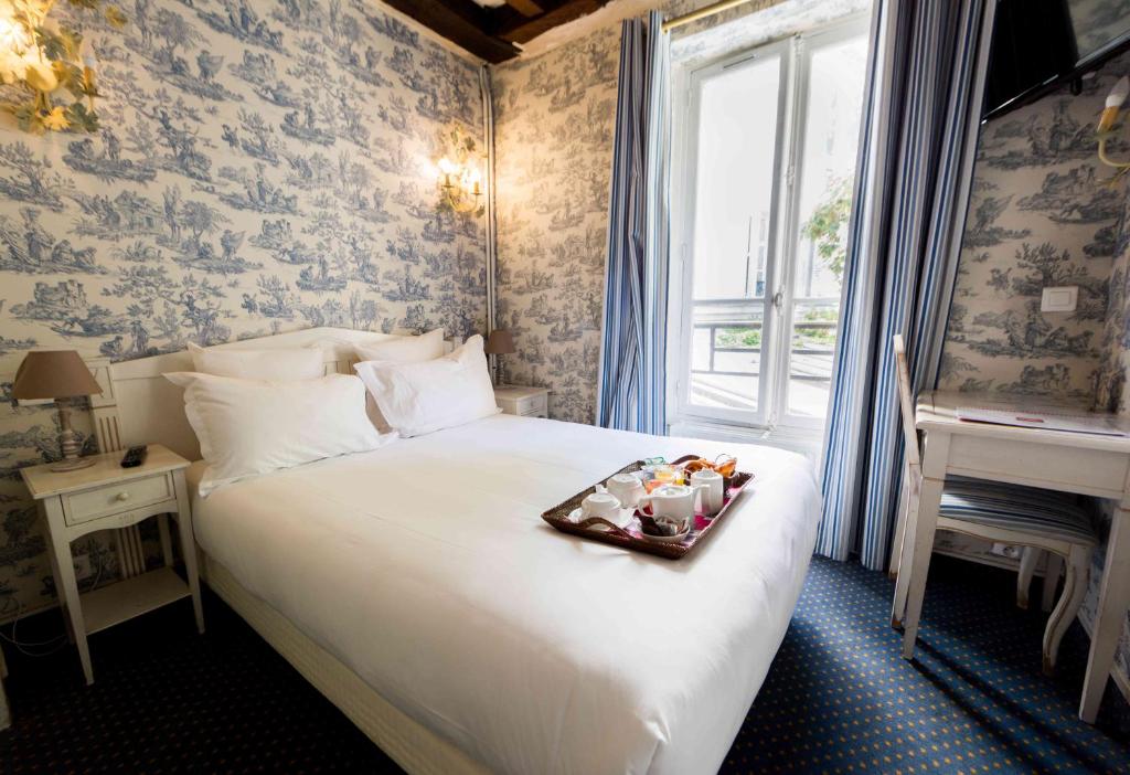 Un dormitorio con una cama con una bandeja de comida. en Regyn's Montmartre en París