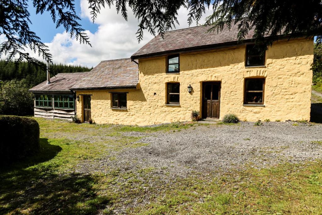 a large yellow brick house on a field at Bryngolau in Brechfa