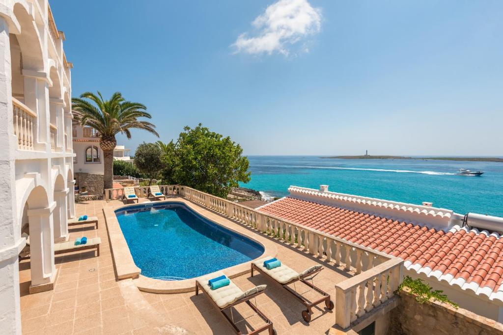 uma piscina com cadeiras e o oceano ao fundo em Villa Torre Vea em Punta Prima