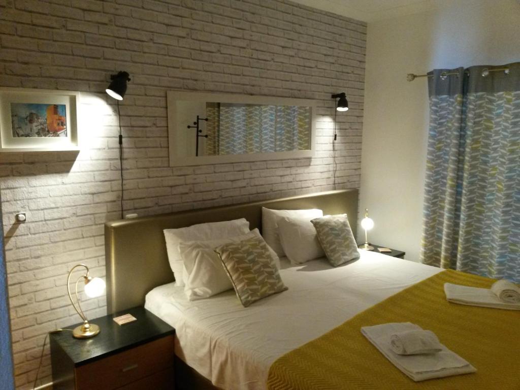 - une chambre avec un grand lit et un mur en briques dans l'établissement Casa Carmela, à Burgau