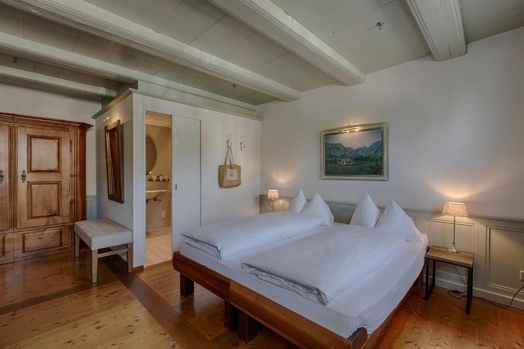 - une chambre avec un grand lit blanc et une salle de bains dans l'établissement Romantik Hotel Bären Dürrenroth, à Dürrenroth