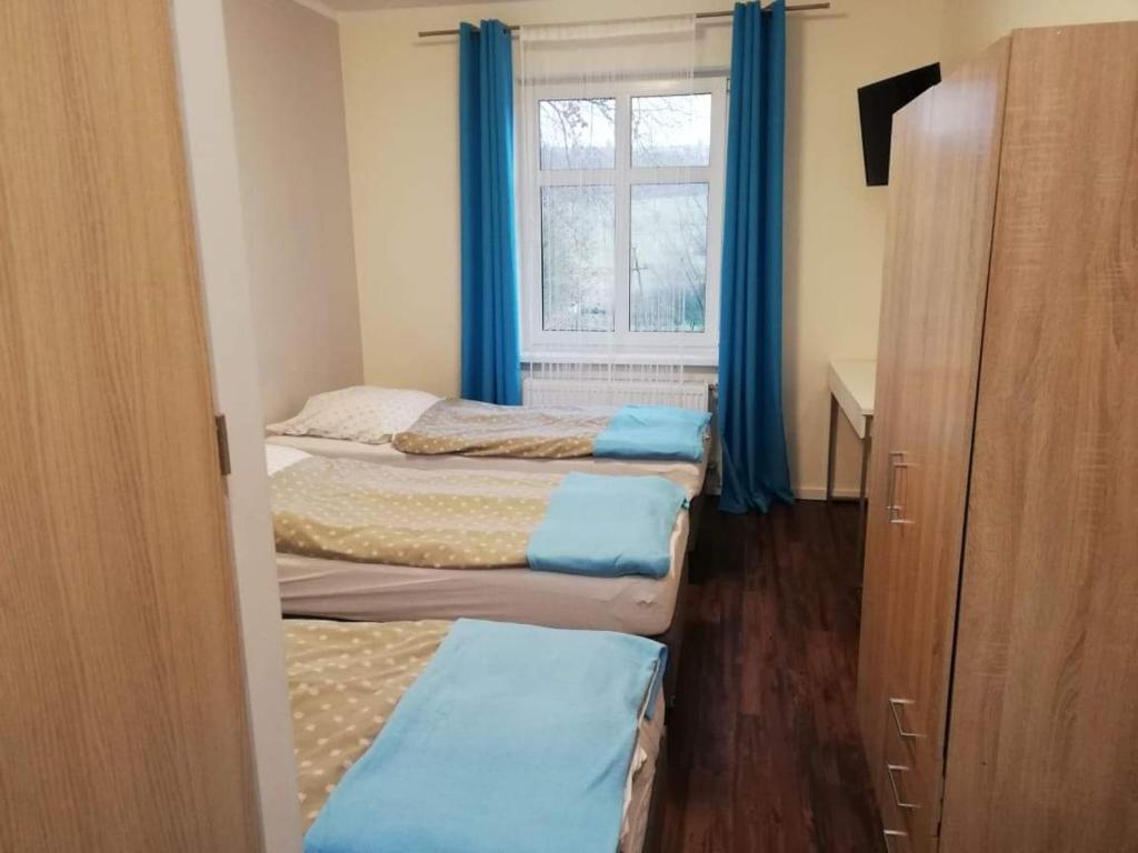 a room with three beds and a window with blue curtains at Willa Wiktoria in Międzylesie