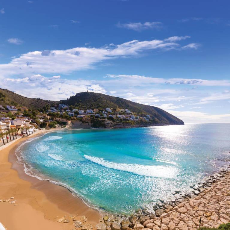 a view of a beach with the ocean and houses at Moraira Beach in Moraira
