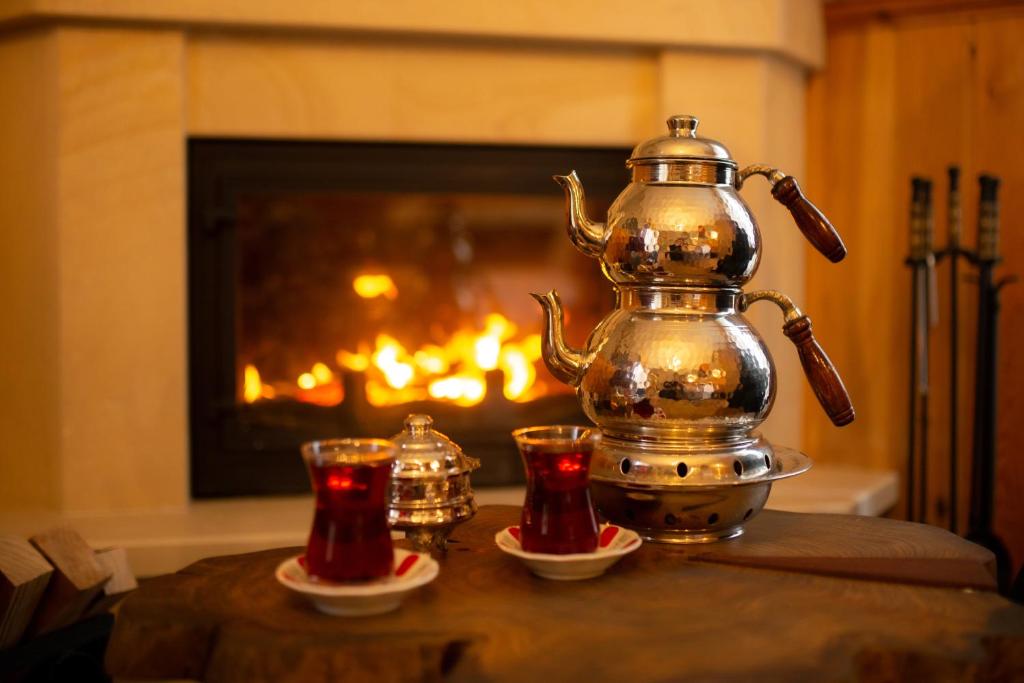 a tea kettle and two cups on a table with a fireplace at Ayder Koru Hotel in Ayder Yaylasi