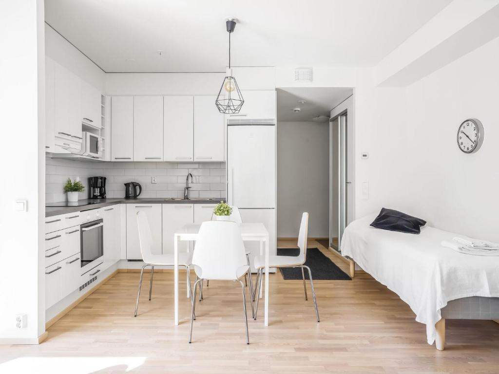 una cucina e una sala da pranzo con letto, tavolo e sedie di Kotimaailma Apartments Tampere a Tampere