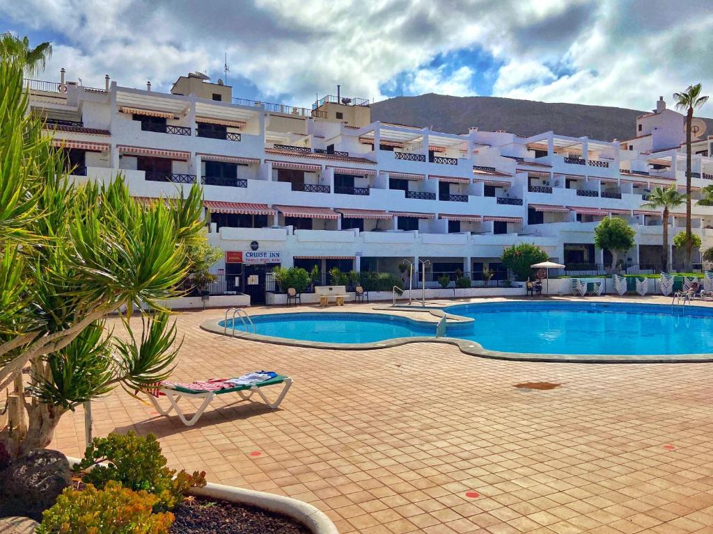 a large hotel with a swimming pool and a building at Victoria Court Modern 1 Bed Apartment Los Cristianos Tenerife in Los Cristianos