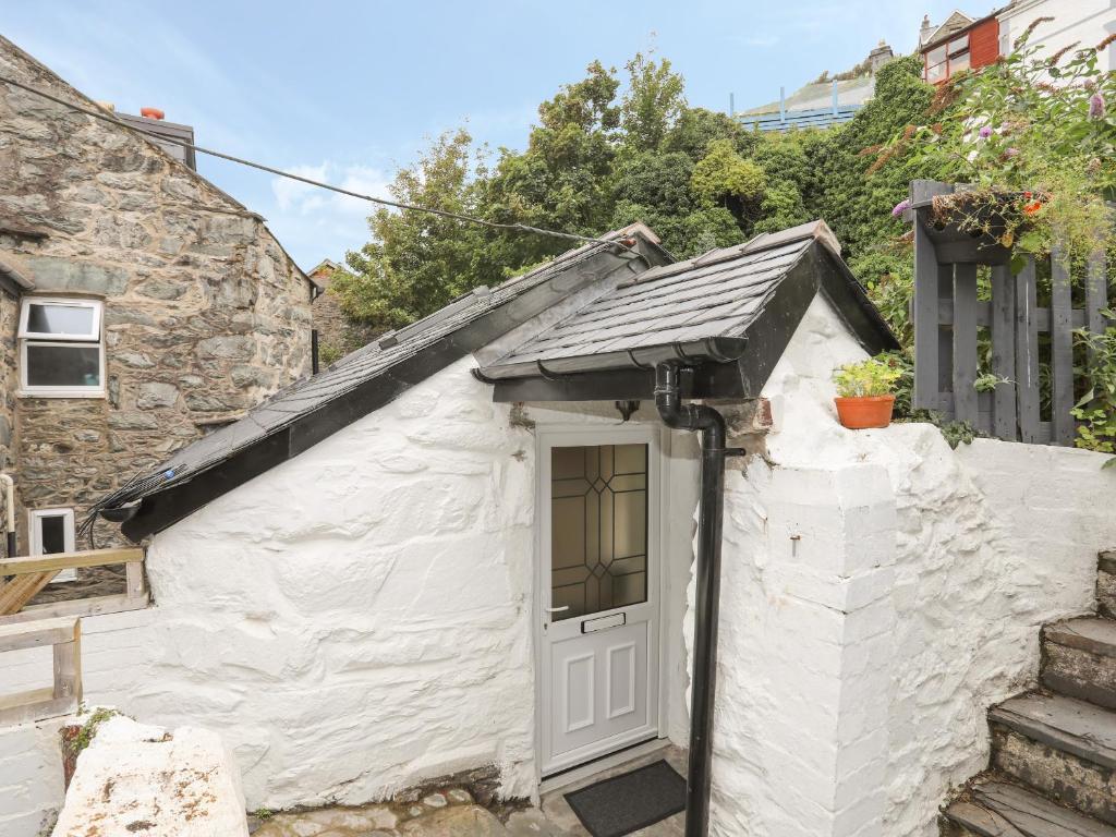 a small white cottage with a door at Glan Meon Cottage in Barmouth