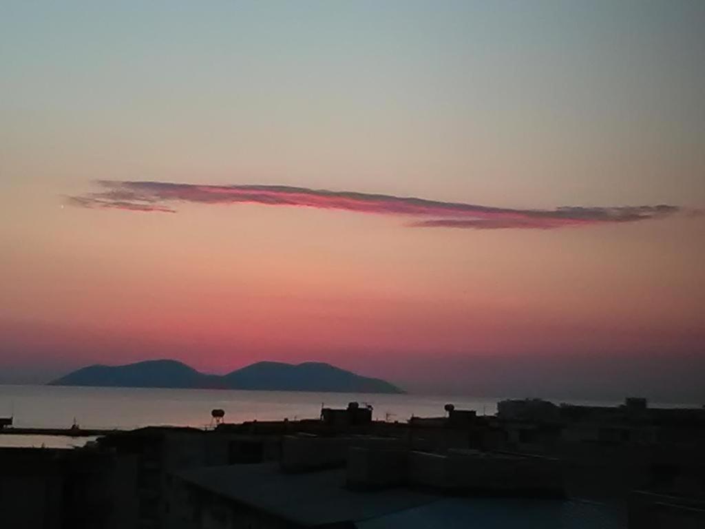 einen Sonnenuntergang über dem Meer mit Bergen im Hintergrund in der Unterkunft Lindita's Seaview Apartment 2 in Vlorë