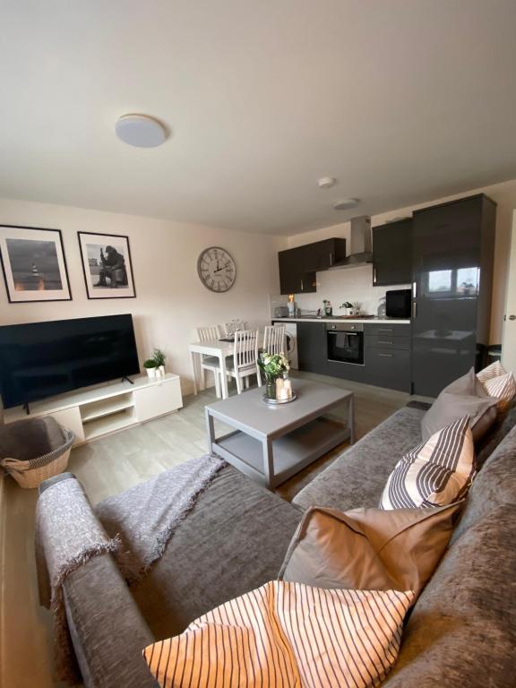 a living room with a couch and a kitchen at Coalhouse Apartment in Seaham