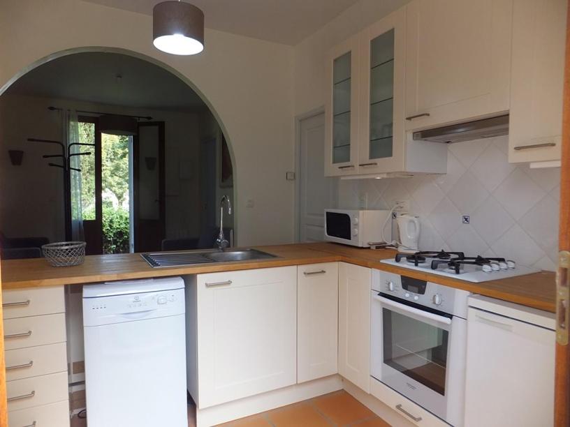 uma cozinha com armários brancos e um forno com placa de fogão em La Maison du Lac em Lignan-de-Bordeaux