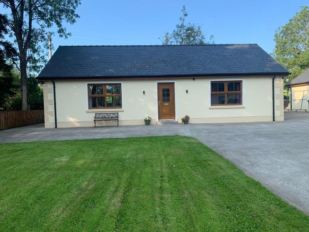 a white house with a bench in front of a yard at Burnmon Cottage in Belcoo