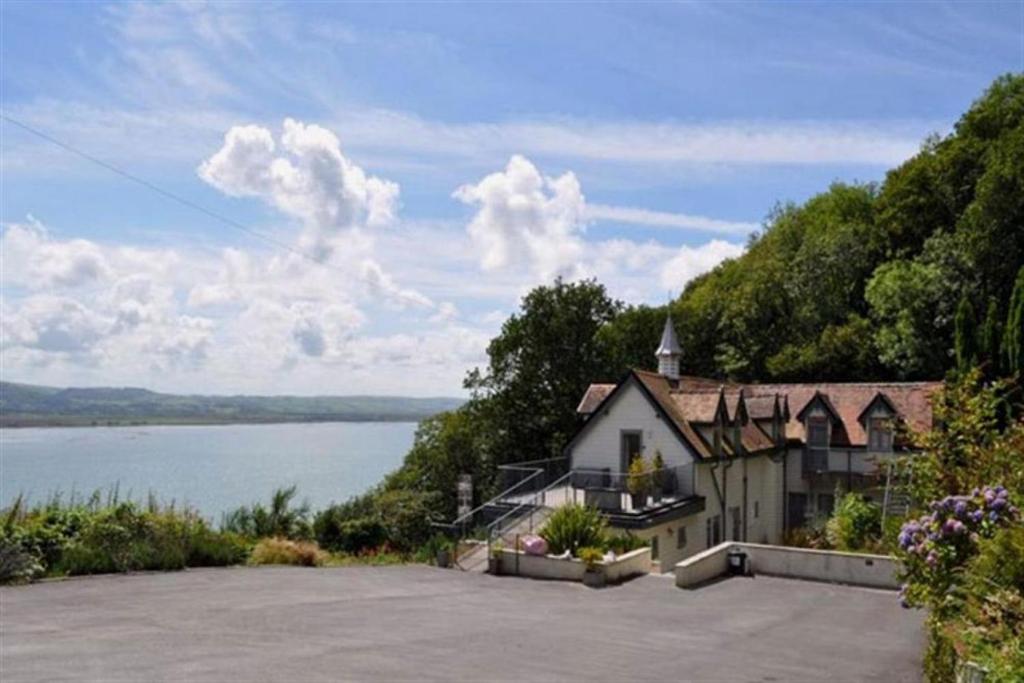 una casa en una colina junto a un cuerpo de agua en The Old Stables Aberdyfi apartment 3 en Aberdyfi