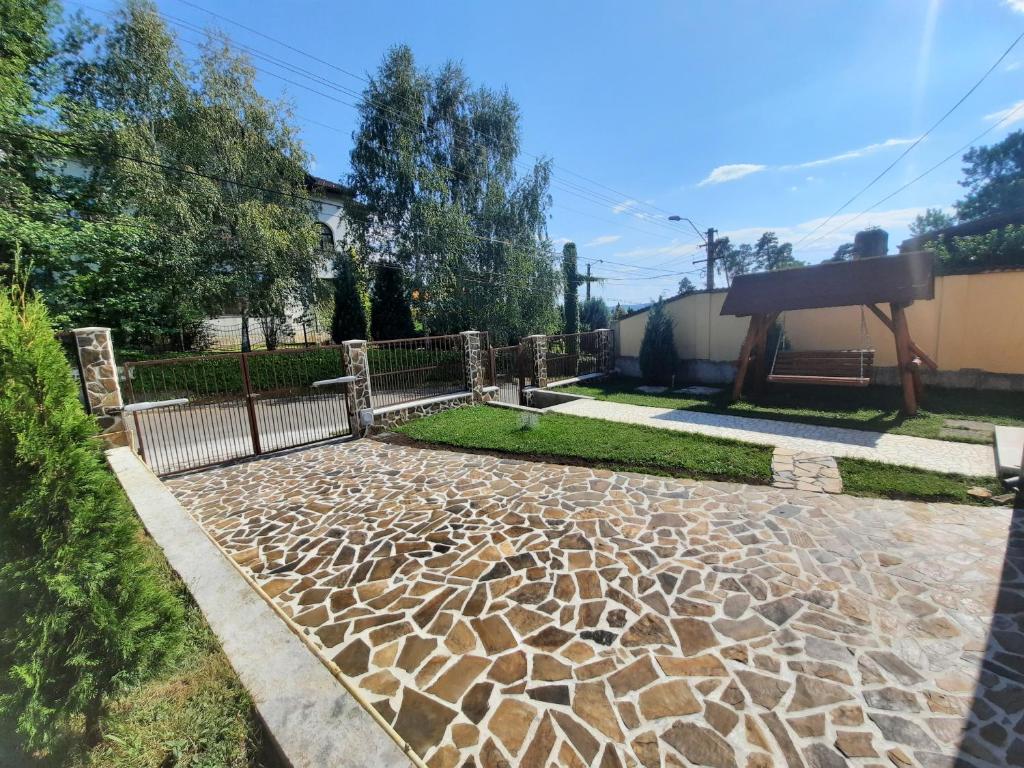 een tuin met een hek en een stenen loopbrug bij Vila San Nicoara in Curtea de Argeş