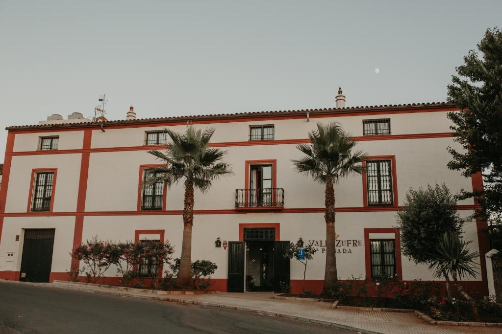 a building with palm trees in front of it at Hotel Posada de Valdezufre in Aracena