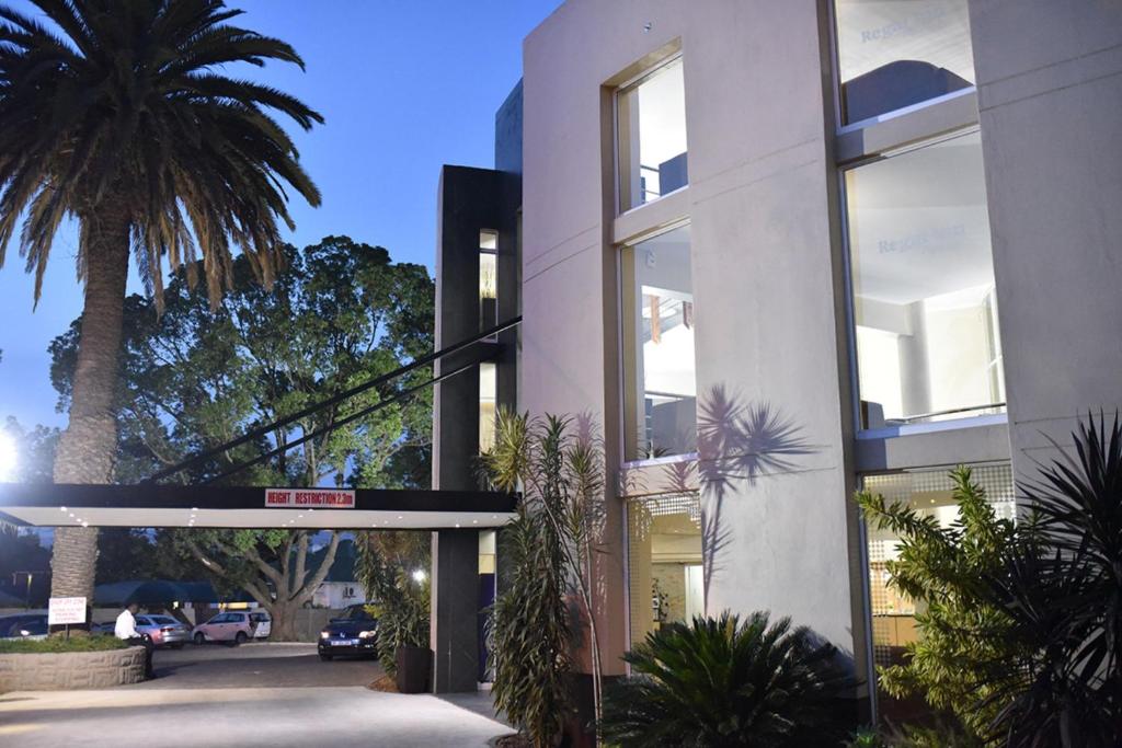 a building with a palm tree in front of it at Regal Inn PMBurg in Pietermaritzburg