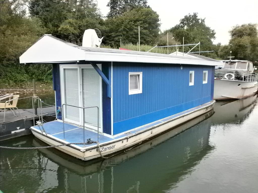 une maison bleue sur un bateau dans l'eau dans l'établissement Sportboot Zander, à Bornheim