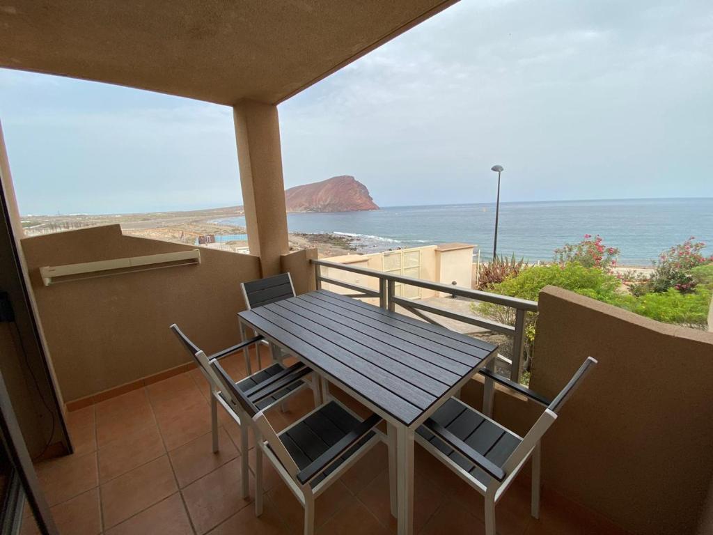 a table and chairs on a balcony with the ocean at HomeForGuest Spacious and bright flat on the beach La Tejita in Granadilla de Abona