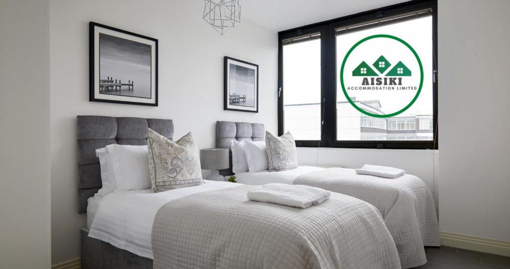 two beds in a white room with a sign at Aisiki Living at Upton Road, Multiple 1, 2, or 3-Bedroom Apartments, King or Twin Beds with Free WiFi & Parking Space in Watford