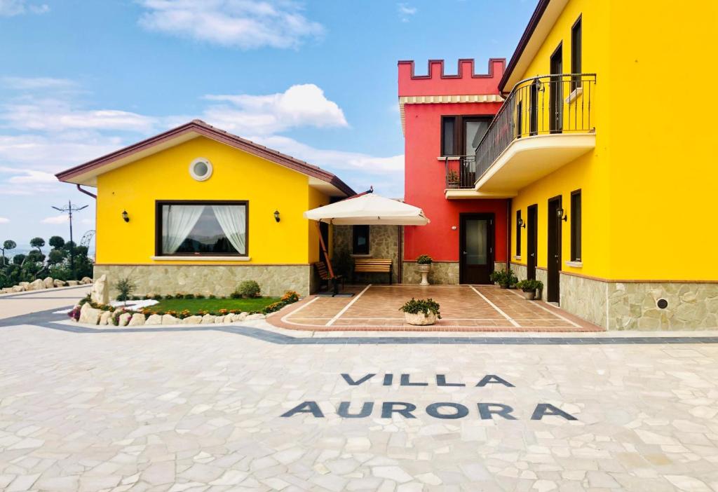 un edificio amarillo y rojo con un letrero que lee willa aurora en Villa Aurora en Villanova del Battista