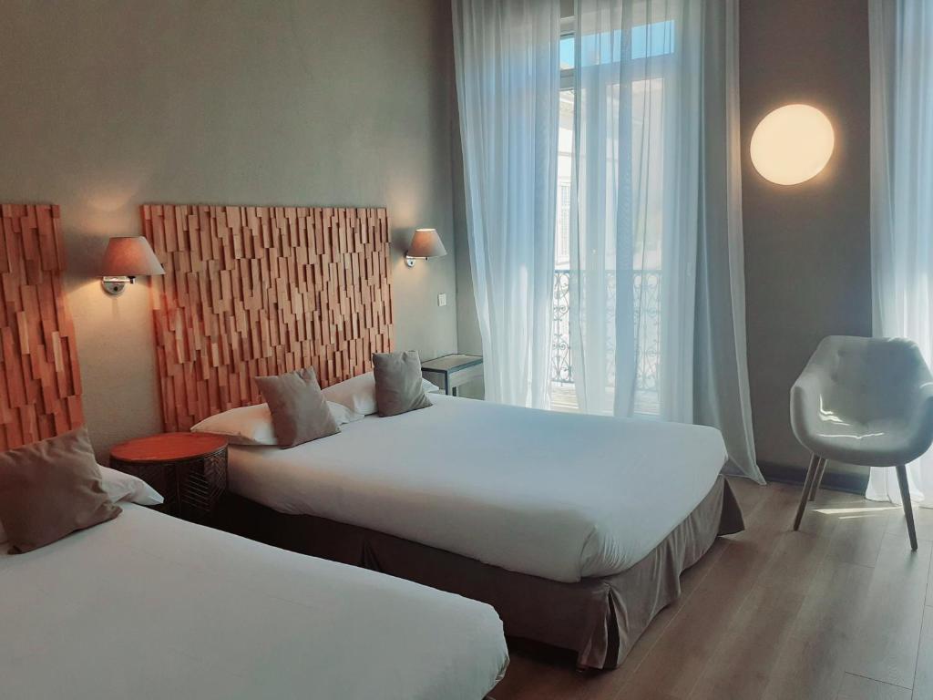 a hotel room with two beds and a window at Hôtel La Villa Tosca in Cannes