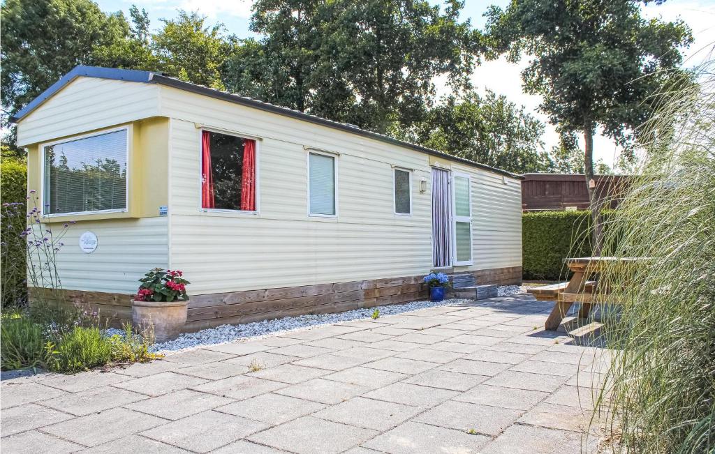 a small white house with a patio in a yard at Nice stacaravan In Tzummarum With Outdoor Swimming Pool in Tzummarum