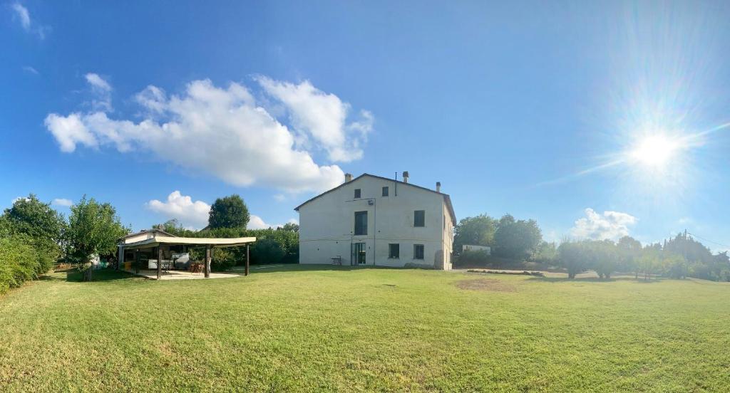 a large white house with a large grass field at R&B Del Monte in Forlì