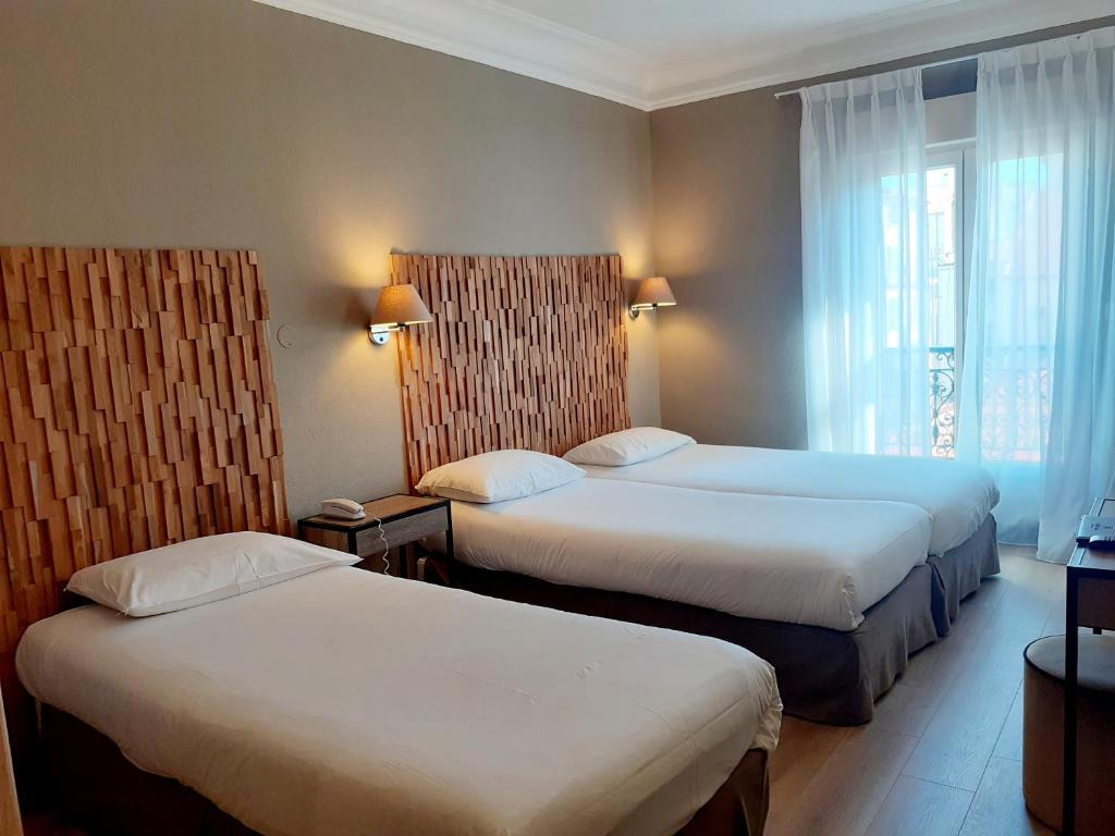a hotel room with two beds and a window at Hôtel La Villa Tosca in Cannes