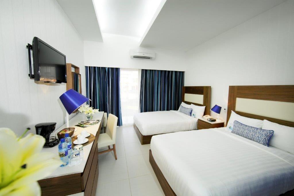 Una habitación de hotel con dos camas y un escritorio con televisión. en Hotel Mykonos, en Santiago de Veraguas