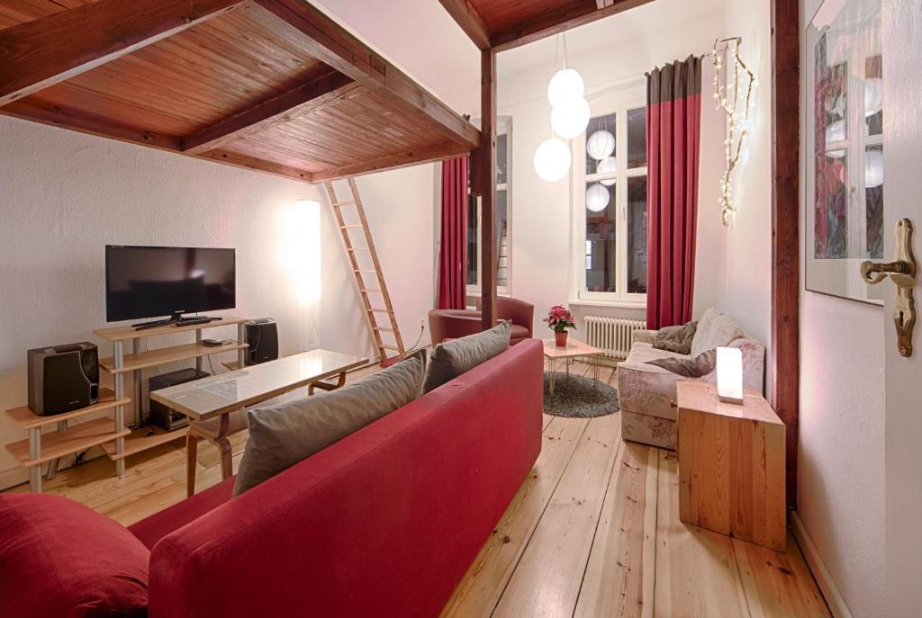 ベルリンにあるRuhige Ferienwohnung in Kreuzbergのリビングルーム(赤いソファ、テレビ付)
