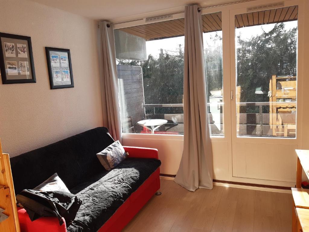 ein Wohnzimmer mit einem Sofa und einem großen Fenster in der Unterkunft Ski Soleil 304 in Manigod
