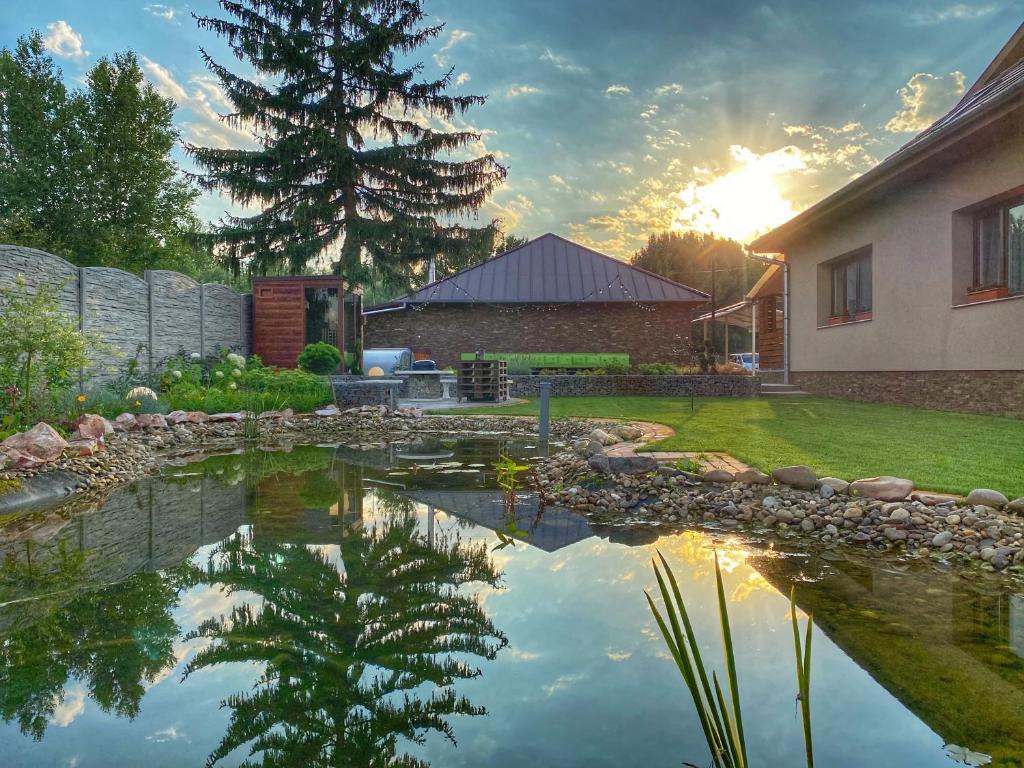 un étang en face d'une maison au coucher du soleil dans l'établissement MADISON RANCH, à Szabolcsveresmart
