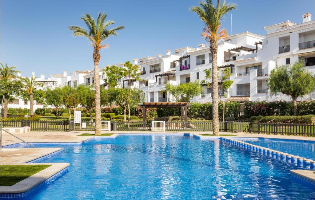 a swimming pool with palm trees and buildings at Lovely Apartment In Roldn With Outdoor Swimming Pool in Los Tomases