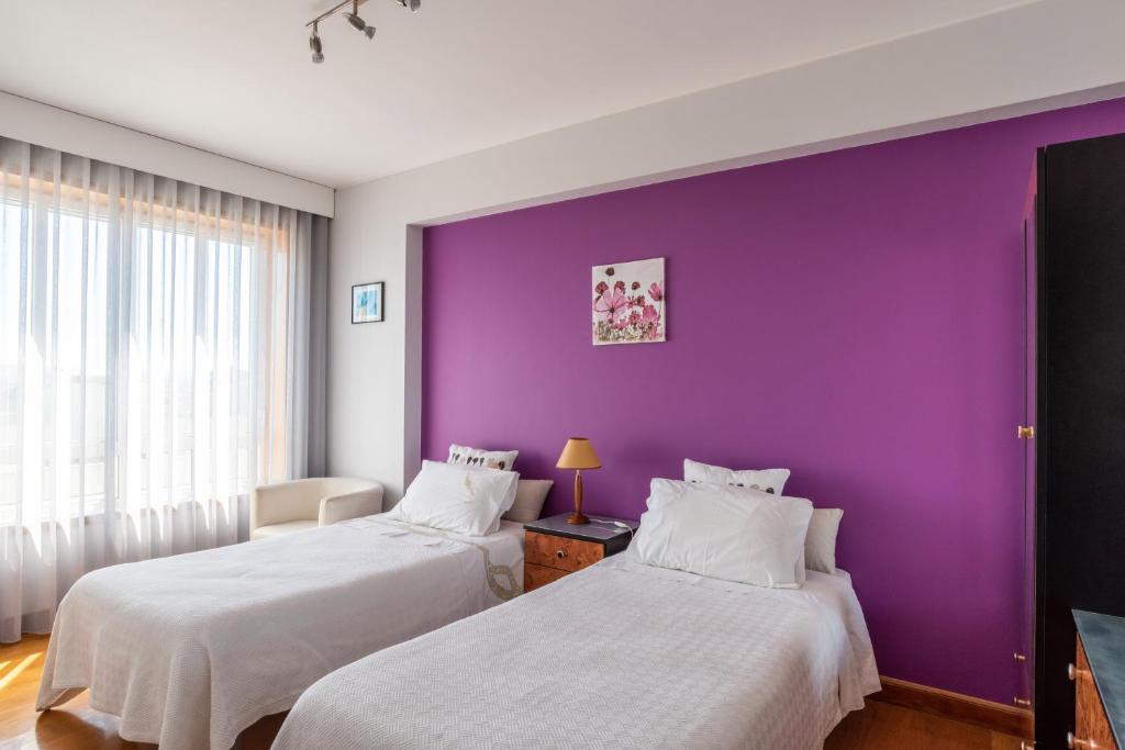 2 camas en una habitación con una pared púrpura en Avenida Apartment by MP, en Vila Nova de Gaia